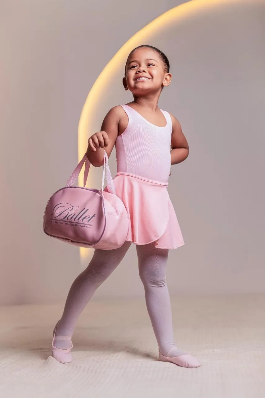 Menina sorrindo em uniforme de balé rosa segurando uma bag oval personalizada.