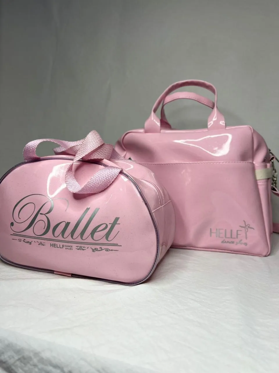 Duas bolsas de dança em verniz rosa, uma com a estampa Ballet e outra com a marca aplicada.