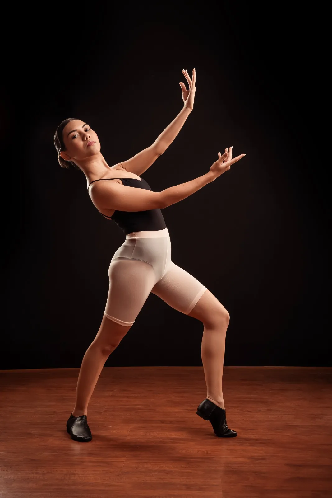 Bailarina adulta em pose de jazz usando short suplex e botinhas pretas de dança.