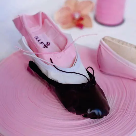Sapatilhas de balé em tecido nas cores rosa, branca e preta, com sola inteira.